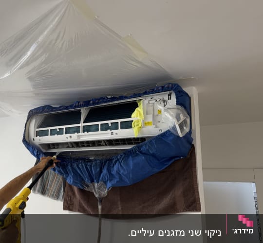 אדם מנקה מזגן עם ציוד מקצועי